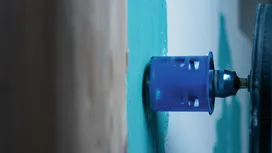 Scie cloche en train de découper une plaque de plâtre sur un mur intérieur peint.